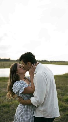 a man and woman kissing in front of a body of water