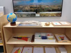 a shelf with some books and pictures on it in front of a television screen that is displaying a cityscape