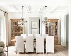 a dining room table with white chairs and chandelier