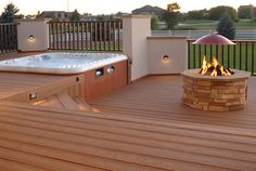 a hot tub sitting on top of a wooden deck next to a fire pit and grill