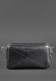 a black leather belt bag on a gray background, with the strap down to it's side