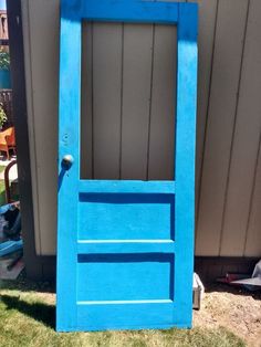 a blue door sitting in the grass next to a building