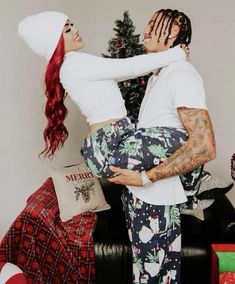 a man holding a woman in his arms near a christmas tree