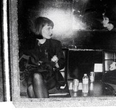 black and white photograph of two women sitting in front of a mirror with bottles on the table