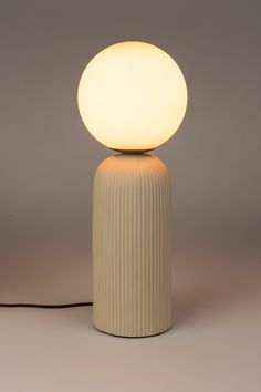 a white lamp sitting on top of a table next to a black corded light