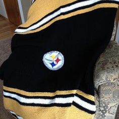 a pittsburgh football blanket sitting on top of a couch next to a chair in a living room