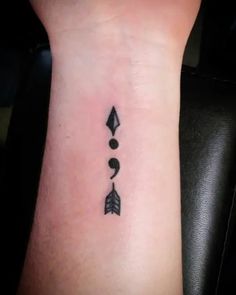 a small arrow tattoo on the wrist with an arrow and two arrows in it,