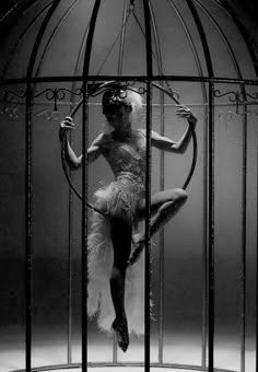 a woman is standing in a cage with feathers