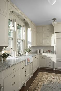 a large kitchen with white cabinets and marble counter tops, along with an area rug on the floor