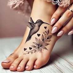 a woman's foot with a bird and flowers tattoo on the side of her leg