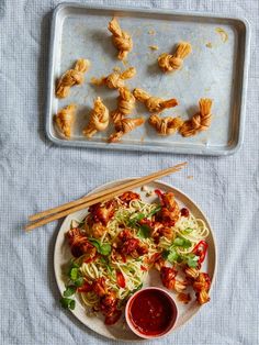 food on a plate with chopsticks next to it and another tray full of food