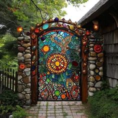 a colorful stained glass gate in the middle of a garden with stone walkway and trees