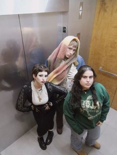 three girls are standing in front of an elevator