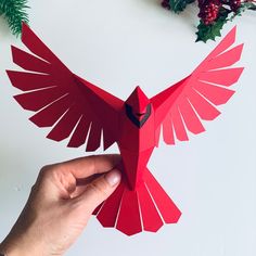 a hand holding up a red paper bird