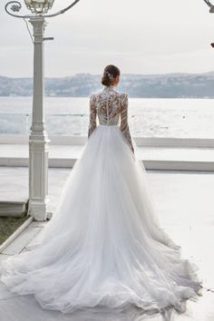 a woman in a wedding dress looking out at the water