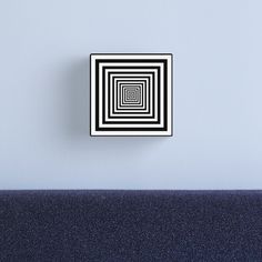 a black and white square in the middle of a room with a blue wall behind it