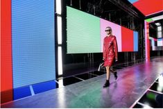 a model walks down the runway in a red leather coat and black boots with sunglasses on