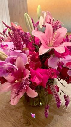 a vase filled with pink flowers on top of a wooden table