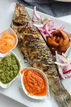 grilled fish with vegetables and sauces on a white plate