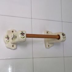 an elephant shaped toothbrush holder on a white tile wall with flowers painted on it