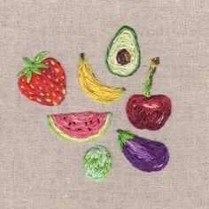 some fruit and vegetables are on a piece of fabric with yarn in the shape of an avocado