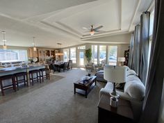 a living room filled with furniture next to a kitchen and dining room table in front of a large window