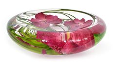 a glass bowl filled with pink flowers and green leaves