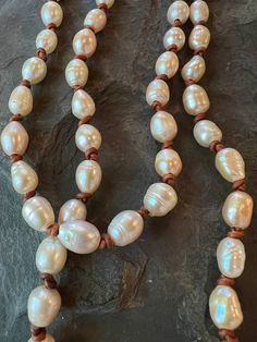 a long necklace with white pearls and brown beads on a black stone slabd surface