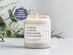 a white candle sitting on top of a table next to some flowers and greenery