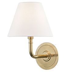 a wall light with a white shade on the side and a gold finish to it