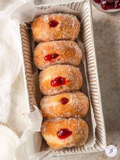 a box filled with donuts covered in powdered sugar and cherry jam sitting on top of a table