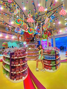 a woman standing in the middle of a store filled with lots of candy and lollipops