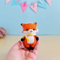 a hand holding a small stuffed animal on top of a table