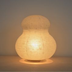 a light that is sitting on top of a table next to a lamp shade in the shape of a vase