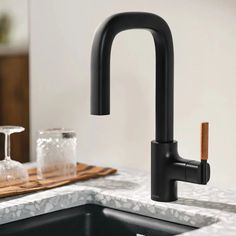 a black faucet in a kitchen with marble counter tops