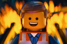 the lego movie character is smiling and holding his arms out in front of yellow flames