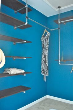 a room with blue walls and shelving in the corner, including shelves that hold clothes