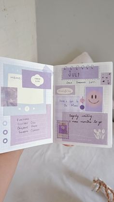 a person holding up a purple and white book with stickers on it's pages