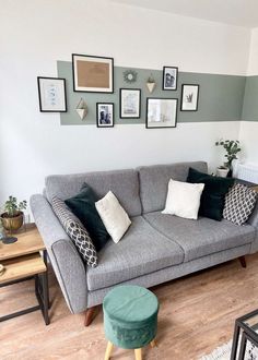 a living room with grey couches and pictures on the wall above them in various frames