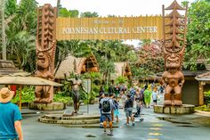 people are walking around in front of an entrance to a tropical cultural center with tiki statues