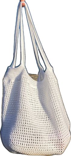 a crocheted white bag hanging from a hook on a string with an orange handle