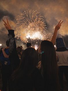 people are watching fireworks in the sky with their hands up and one person is raising his hand