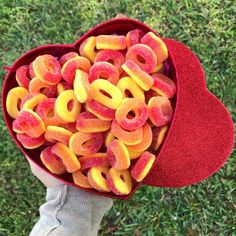 a person holding a heart shaped box filled with fruit