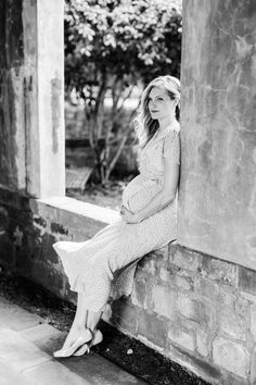 a pregnant woman sitting on the side of a building