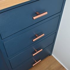 a blue dresser with copper handles and knobs