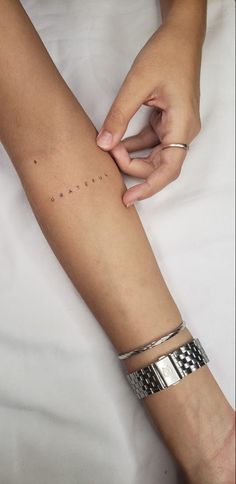 a person is holding onto their arm with two bracelets on it and the other arm has small black dots