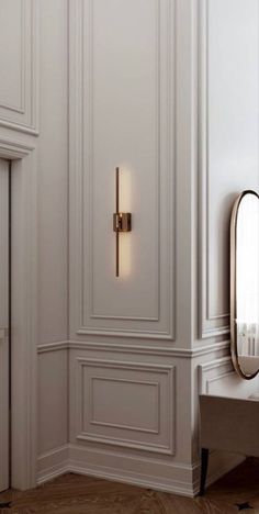 an elegant bathroom with white walls and wood flooring, gold trimming on the door