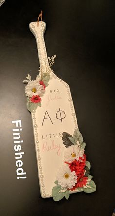 a bottle shaped sign with flowers on it