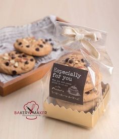 some cookies are wrapped in plastic and sitting on a wooden tray next to a bag