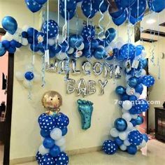 blue and white balloons are hanging from the ceiling in front of a welcome baby sign